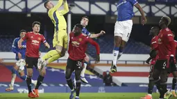 Kiper Manchester United, Dean Henderson melompat menangkap bola dari sundulan gelandang Everton, Yerry Mina pada babak perempat final di Goodison Park, Kamis (24/12/2020). Dengan kemenangan ini, MU berhasil melaju ke semifinal Piala Lifa Inggris 2020-2021. (AP Photo/Nick Potts,Pool)