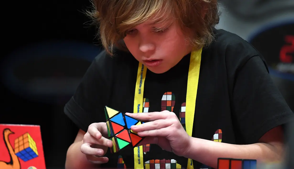Seorang anak laki-laki serius memecahkan permainan rubik pada kejuaraan kubus Rubik Dunia di Melbourne, Australia (12/7/2019). Permainan Kubus Rubik 3x3x3, ditemukan oleh Profesor Rubik dari Hongaria pada tahun 1974. (AFP Photo/William West)
