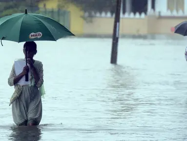 Warga menggunakan payung melewati jalanan yang tergenang banjir akibat hujan lebat di Colombo, Senin (16/5). Banjir dan tanah longsor di Sri Lanka menelan sedikitnya delapan korban jiwa, termasuk seorang bayi berusia 10 bulan. (Lakruwan Wanniarachchi/AFP)
