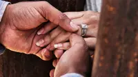 Rogelio memasangkan cincin kawin pada jari istrinya, Miriam saat menikah melalui dinding perbatasan antara Meksiko dan Amerika Serikat di Ciudad Juarez, 10 Desember 2017. Mereka dipisahkan karena undang-undang imigrasi yang ketat. (Herika MARTINEZ/AFP)