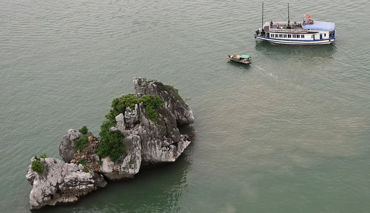 Kapal wisata berlayar di perairan Ha Long Bay, Provinsi Quang Ninh, Vietnam, Jumat (10/5/2019). Kendati indah, Ha Long Bay tidak berpenghuni sebab sebagian pulau-pulau tersebut terjal dan tandus oleh batuan kapur. (Manan VATSYAYANA/AFP)