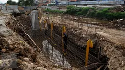 Pekerja memasang besi untuk pembangunan jalan inspeksi Sungai Ciliwung di Cililitan Kecil, Jakarta, Kamis (22/12). Pembangunan jalan tersebut sebagai salah satu solusi mengatasi kemacetan di Ibukota (Liputan6.com/Gempur M Surya)