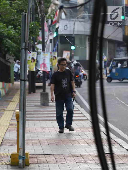 Pejalan kaki melintasi trotoar yang terhalang instalasi kabel di Jalan Kyai Maja, Jakarta, Rabu (10/4). Selain menganggu kenyamanan pejalan kaki, kondisi instalasi kabel yang semrawut tersebut juga berbahaya apabila mengandung aliran listrik. (Liputan6.com/Immanuel Antonius)
