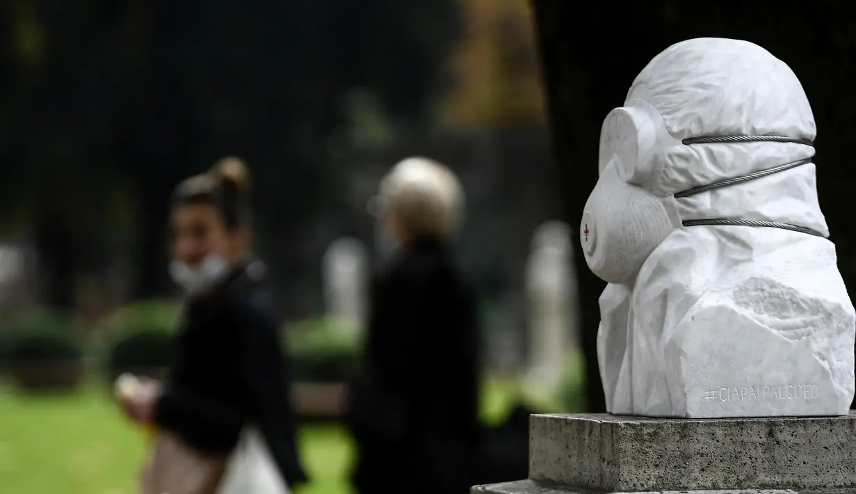 Wanita yang memakai masker wajah berjalan di dekat patung marmer yang didedikasikan untuk dokter, perawat, dan petugas kesehatan tanpa judul "Tentara anti Covid-19", di Taman Pincio di Roma tengah (4/11/2020). (AFP/Filippo Monteforte)