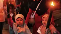 Anak-anak membawa obor sambil berkeliling kampung di kawasan Kota Tangerang, Banten, Jumat (29/7/2022) malam. Pawai obor tersebut digelar untuk menyambut malam pergantian Tahun Baru Islam atau 1 Muharam 1444 H. (Liputan6.com/Angga Yuniar)