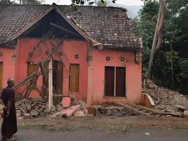 Warga melihat rumah yang rusak usai gempa melanda Pandeglang, Banten, Sabtu (3/8/2019). Menurut data sementara BPBD, sebanyak 106 unit rumah di Kabupaten Pandeglang dan Lebak rusak usai gempa Banten berkekuatan magnitudo 6,9. (RONALD SIAGIAN/AFP)