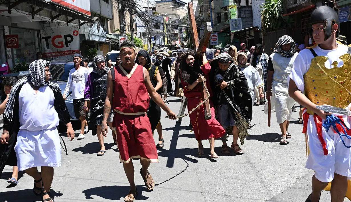 Seorang aktor yang berperan dalam sebuah drama jalanan sebagai Yesus membawa salib kayu saat peragaan penderitaan dan penyaliban pada Pekan Suci di Manila pada 28 Maret 2024. (Ted ALJIBE/AFP)