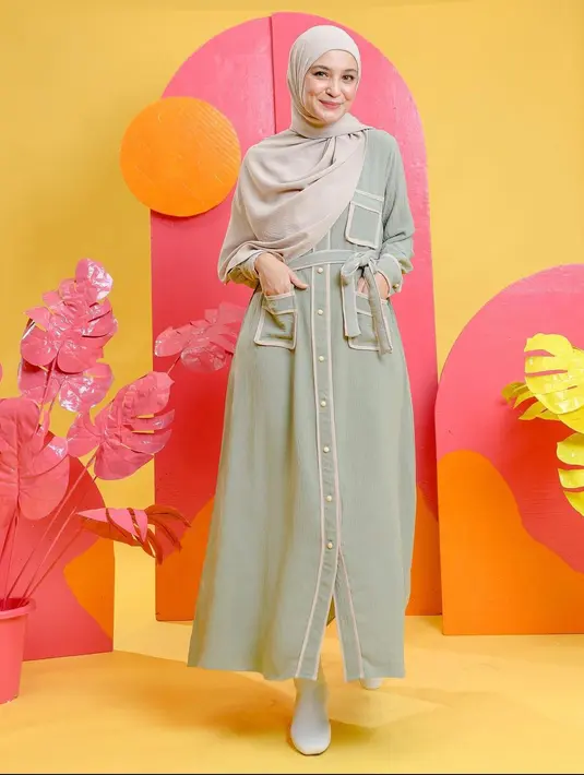Hadir dengan nuansa pastel adalah pilihan yang tepat, lho. Kamu dapat mengenakan gamis berwarna sage green dengan detail list nude pada saku, belt dan kancing. (instagram/shireensungkar)