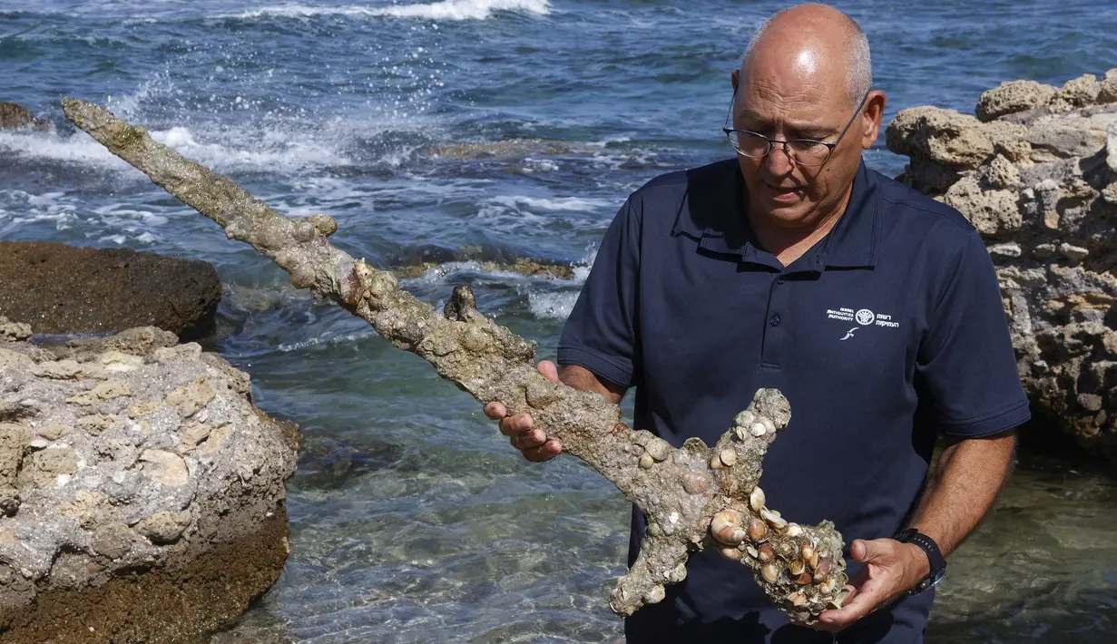 Jacob Sharvit dari Israel Antiquities Authority memperlihatkan pedang berusia 900 tahun yang diyakini milik seorang tentara salib di Caesarea pada 19 Oktober 2021. Seorang penyelam amatir menemukan pedang tersebut dari dasar laut Mediterania.  (JACK GUEZ / AFP)