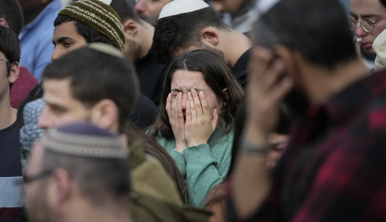 Para pelayat bereaksi selama pemakaman Hillel Yaniv (21) dan Yagel Yaniv (19) di pemakaman nasional Israel di Yerusalem, Senin, 27 Februari 2023. Kedua bersaudara Israel itu dibunuh pada Minggu di kota Hawara, Tepi Barat, oleh seorang warga Palestina. penembak yang melarikan diri dari tempat kejadian. (AP/Ohad Zwigenberg)