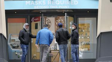 Orang-orang berjalan ke pintu masuk di Space Needle di bawah tanda bertuliskan "Masker Diperlukan" di Seattle pada 17 Februari 2022. Gubernur Jay Inslee mengatakan mandat masker dalam ruangan di negara bagian Washington akan dicabut pada 21 Maret 2022 mendatang. (AP Photo/Ted S. Warren)