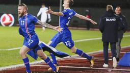 Pemain Islandia, Aron Einar Gunnarsson dan Jon Dadi Bodvarsson melakukan selebrasi usai memastikan negaranya lolos Piala Dunia 2018 di Stadion Laugardalsvöllur, Senin (9/10/2017). Islandia menang 2-0 atas Kosovo. (AP/Brynjar Gunnarsson)