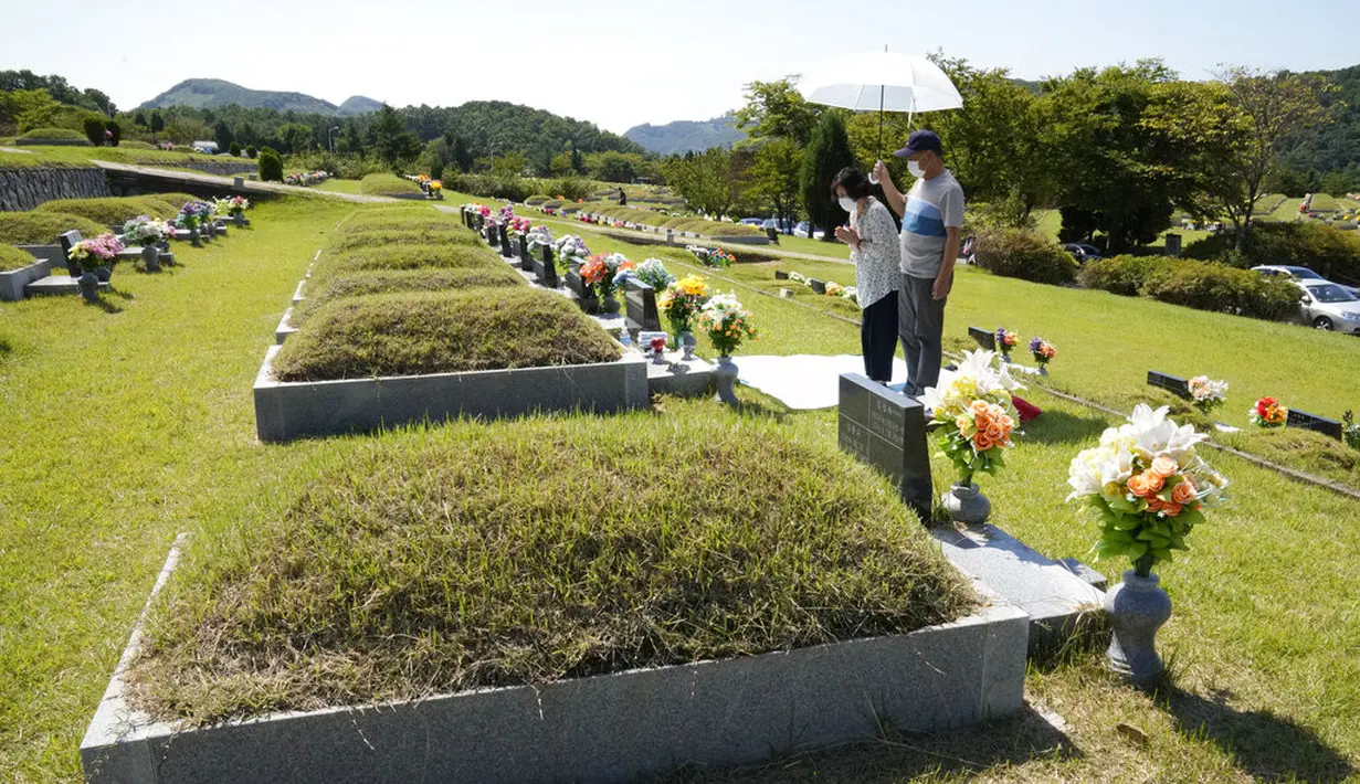 Anggota keluarga memberi penghormatan kepada pemakaman leluhur mereka menjelang liburan Chuseok di sebuah pemakaman di Paju, Korea Selatan (12/9/2021).  Pemakaman nasional Korea Selatan akan ditutup selama liburan Chuseok. (AP Photo/Ahn Young-joon)