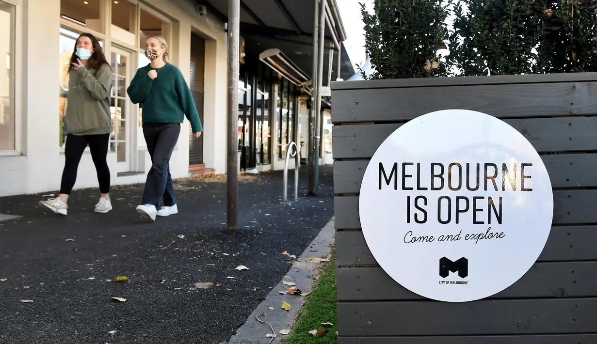 Orang-orang berjalan melewati tanda di kafe dan restoran Lygon Street di Melbourne, Rabu (2/6/2021). Kota Melbourne dan wilayah lainnya di negara bagian Victoria, Australia, akan mengalami perpanjangan lockdown yang tadinya dijadwalkan berakhir pada Kamis (3/6/2021) malam. (William WEST / AFP)