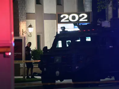 Seorang petugas polisi berdiri di luar gedung perkantoran di mana beberapa orang tewas dalam penembakan di Orange, California (31/3/2021).  Pihak berwenang mengatakan bahwa empat orang, termasuk seorang anak, tewas dalam penembakan dan dua lainnya telah diangkut ke rumah sakit setempat. (AFP/Patrick