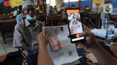 Petugas memotret warga penerima Bantuan Sosial Tunai (BST) di SDN Pondok Cabe Udik 03, Tangerang Selatan, Rabu (28/07/2021). Lebih dari dari 1800 warga mendapatkan BST yang dirapel dua bulan sekaligus dengan total Rp600ribu. (merdeka.com/Arie Basuki)