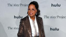 Oprah Winfrey menghadiri pemutaran perdana The 1619 Project di Academy Museum of Motion Pictures, Los Angeles, California, Amerika Serikat, 26 Januari 2023. Wanita berusia 68 tahun tersebut mengenakan atasan berkancing putih di dalam mantel cokelatnya. (VALERIE MACON/AFP)