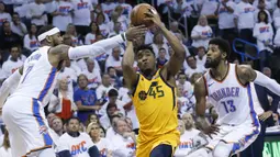 Pebasket Utah Jazz, Donovan Mitchell, berusaha melewati pebasket Oklahoma City Thunder, Carmelo Anthony, pada gim kedua play-off NBA Wilayah Barat, Rabu (18/4/2018). Jazz menang 102-95 atas Thunder. (AP/Sue Ogrocki)