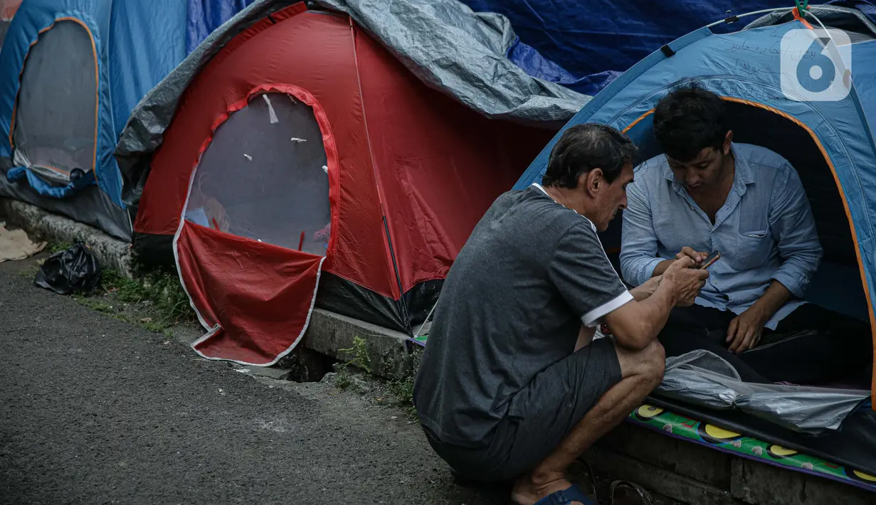 Pengungsi Afghanistan berbincang di tenda yang didirikan di trotoar Kawasan Kebon Sirih, Jakarta, Kamis (26/8/2021). Sebanyak 20 pengungsi asal Afghanistan kembali menempati trotoar dengan harapan bisa diterbangkan ke negara lain. (Liputan6.com/Faizal Fanani)