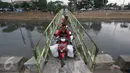 Pengendara motor menyeberangi Kanal Banjir Barat (KBB) di kawasan Tanah Abang, Jakarta, Jumat (30/12). Tidak tersedianya fasilitas penyeberangan lain membuat warga serta pengendara harus berbagi jalan. (Liputan6.com/Immanuel Antonius)
