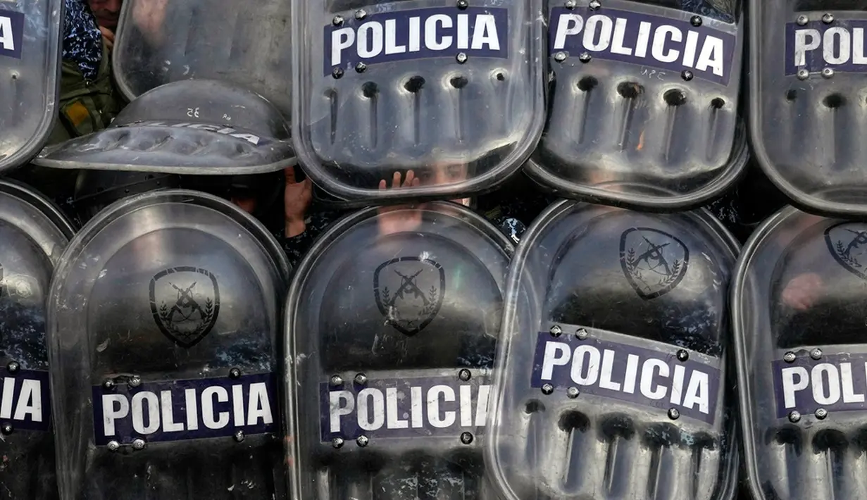 Polisi berlindung menggunakan perisai saat para demonstran melempari mereka dengan batu saat protes terhadap kematian gadis berusia 11 tahun Morena Dominguez di luar kantor polisi di pinggiran Buenos Aires, Argentina, Rabu (9/8/2023). (AP Photo/Natacha Pisarenko)
