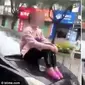 Seorang wanita duduk di kap mesin mobil yang melaju usai bertengkar dengan sang suami. 