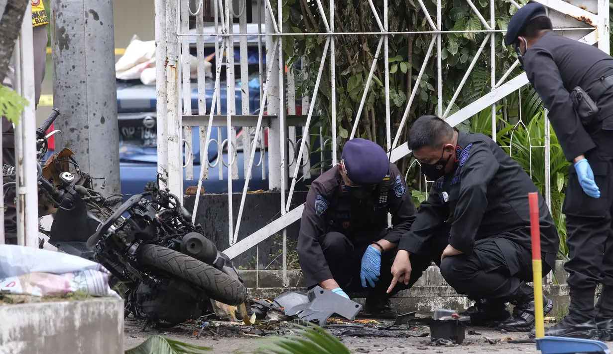 Tim penjinak bom memeriksa puing-puing sepeda motor yang digunakan untuk aksi bom bunuh diri di Gereja Katedral Makassar, Sulawesi Selatan, Senin (29/3/2021). Kepolisian masih melakukan olah TKP serta mengumpulkan serpihan sisa ledakan pada hari kedua pascakejadian. (AP/Masyudi S. Firmansyah)