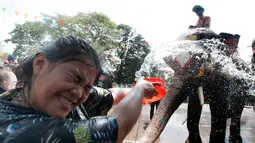 Seorang wanita menyiramkan air dalam perayaan festival air Songkran di provinsi Ayutthaya, utara Bangkok, Thailand, (11/4). Selama perayaan Songkran, warga melakukan perang air di jalanan dan di tempat umum. (AP Photo/Sakchai Lalit)