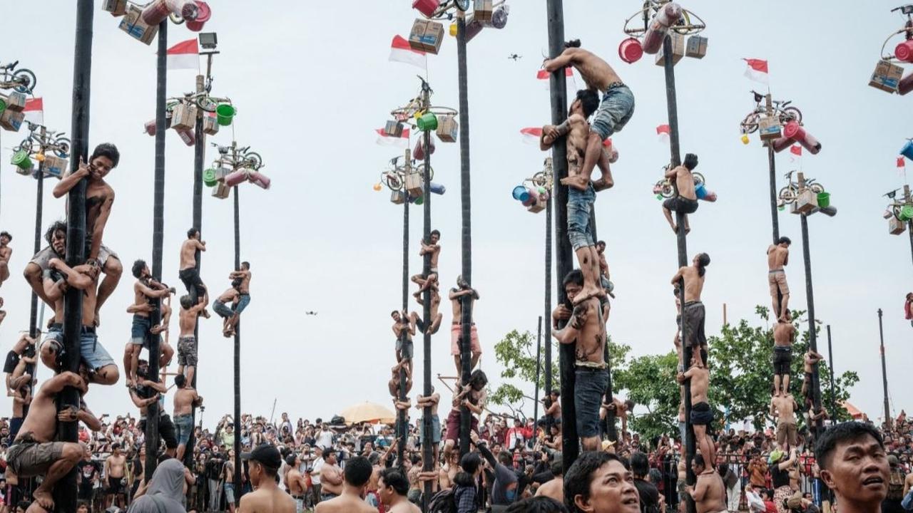 Di samping festival dan pawai budaya, berbagai ajang perlombaan juga diadakan untuk menambah semarak perayaan. Salah satunya lomba panjat pinang yang paling diminati oleh masyarakat. Foto:&nbsp;Yasuyoshi CHIBA / AFP