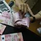 Teller menunjukkan mata uang rupiah di penukaran uang di Jakarta, Rabu (10/7/2019). Nilai tukar rupiah terhadap dolar Amerika Serikat (AS) ditutup stagnan di perdagangan pasar spot hari ini di angka Rp 14.125. (Liputan6.com/Angga Yuniar)