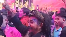 Dalam foto yang tersebar, Limbad terlihat berdiri di antara kerumunan penggemar JKT48. Pakaian hitam dengan aksen etnik serta sorban khas menghiasi penampilannya. Meski ramai, ia tidak ikut menyanyi, hanya bergoyang pelan menikmati irama lagu yang dibawakan. (Liputan6.com/IG/@limbadindonesia)
