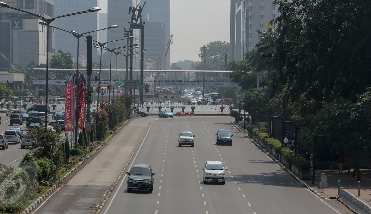 Sejumlah kendaraan bermotor melintasi kawasan Jalan Thamrin mengarah ke Sudirman, Jakarta, Kamis (18/6/2015). Pada hari pertama puasa Ramadan 1436 H, beberapa titik jalan terlihat lengang dan sepi dari aktivitas warga. (Liputan6.com/Faizal Fanani)