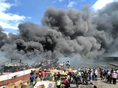 Petugas pemadam kebakaran dibantu pekerja mencoba memadamkan api di kapal nelayan di Pelabuhan Benoa, Denpasar, Bali, Senin (9/7). Kebakaran terjadi pada pukul 02.00 Wita. (SONNY TUMBELAKA/AFP)