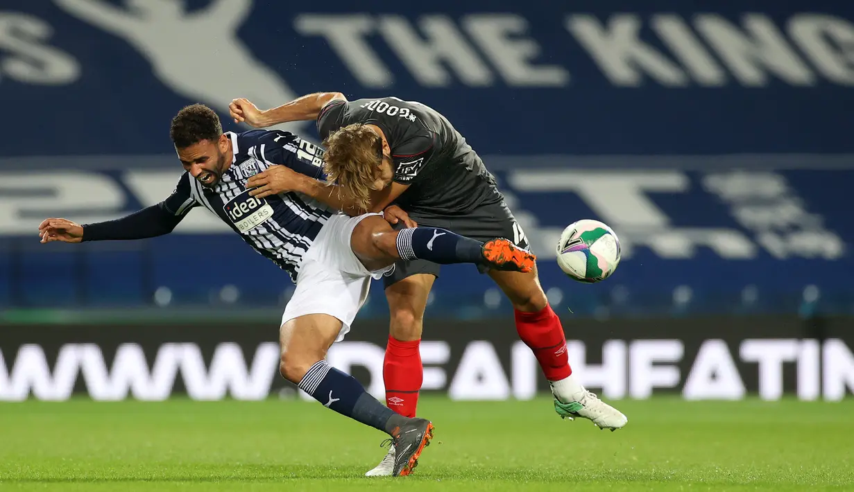 Striker West Brom, Robson-Kanu, berebut bola dengan bek Brentford, Charlie Goode, dalam laga Piala Inggris di venue The Hawthorns, Rabu (23/9/2020) dini hari WIB. West Brom kalah 6-7 atas Brentford lewat adu penalti. (AFP/Carl Recine/pool)