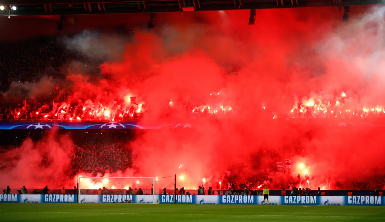 Pendukung Paris Saint-Germain menyalakan suar saat PSG melawan Real Madrid di pertandingan Liga Champions leg kedua di stadion Parc des Princes di Paris (6/3). Mereka juga menyanyikan lagu bernada cemoohan kepada Real Madrid. (AP Photo / Francois Mori)