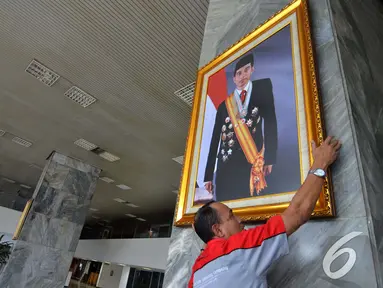 Petugas memasang foto Presiden Jokowi di pilar Gedung Nusantara III Kompleks Parlemen Senayan, Selasa (23/12/2014). (Liputan6.com/Andrian M Tunay)