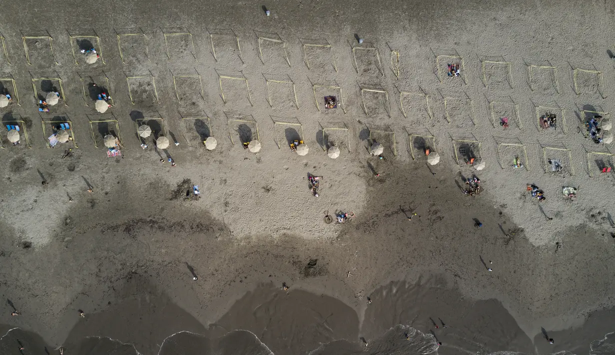 Para pengunjung berjemur dalam pembatas untuk menghindari keramaian di tengah pandemi COVID-19 di Pantai Lima, Peru, Rabu (21/12/2021). Di pantai-pantai populer di Lima, pihak berwenang memutuskan membuat pembatas untuk mencegah kerumunan pengunjung. (Ernesto BENAVIDES/AFP)
