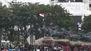 Massa aksi demo tolak omnibus law UU Cipta Kerja naik ke atas patung arjuna wiwaha mengibarkan bendera merah putih di Jalan Medan Merdeka Barat, Jakarta Pusat, Selasa (20/10/2020). Mereka sempat mengibarkan bendera selama kurang lebih lima menit di atas patung. (Liputan6.com/Herman Zakharia)