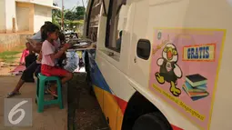 Sejumlah anak membaca buku di mobil perpustakaan keliling di halaman Rusun Cipinang Besar Selatan, Jakarta, Rabu (27/4). Keberadaan perpustakaan keliling tersebut diharapkan dapat menumbuhkan minat baca usia dini. (Liputan6.com/Gempur M Surya)