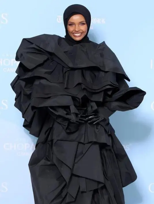 Atau penampilan megah Halima Aden di foto ini. Ia mengenakan outfit dengan aksen tumpuk yang dramatis, berwarna hitam. [Foto: Instagram/halima]