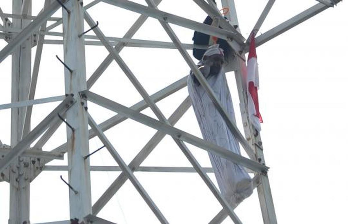 Pria berpakaian pocong di atas tower SUTET