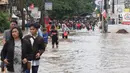 Warga melintasi banjir yang menggenangi Jalan KH Hasyim Ashari, Tangerang, Banten, Kamis (2/1/2020).Banjir yang menggenangi jalan penghubung Jakarta- Tangerang tersebut mulai surut dan sudah bisa dilintasi pejalan kaki. (Liputan6.com/Angga Yuniar)