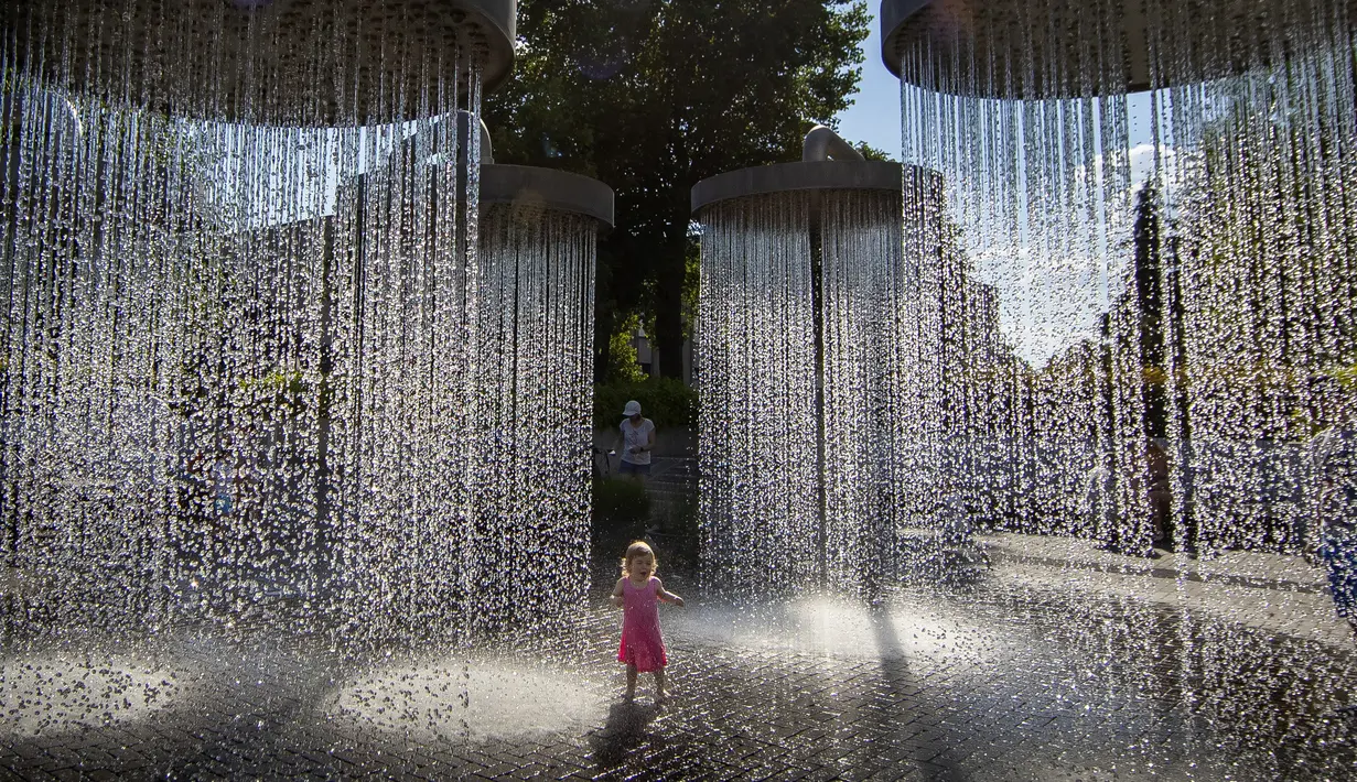 Seorang anak mendinginkan diri di air mancur umum di Vilnius, Lithuania, 26 Juni 2022. Gelombang panas berlanjut di Lithuania saat suhu naik hingga 32 derajat Celcius (89,6 derajat Fahrenheit). (AP Photo/Mindaugas Kulbis)