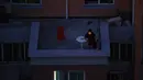 Seorang pria melihat smartphone-nya di balkon di sebuah komunitas perumahan di Shanghai, China (11/4/2022). AS telah memerintahkan semua staf konsuler non-darurat untuk meninggalkan Shanghai, yang berada di bawah penguncian ketat untuk menahan lonjakan COVID-19. (AP Photo)