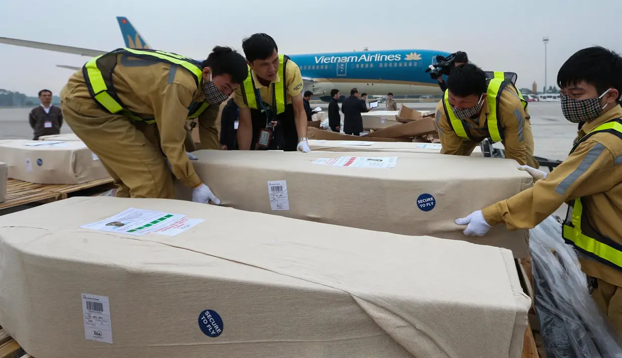 Petugas memasukkan peti mati berisi jenazah yang ditemukan tewas dalam truk kontainer di Inggris ke dalam ambulans setibanya di bandara internasional Noi Bai, Hanoi, Rabu (27/11/2019). Sebanyak 16 dari 39 jenazah telah tiba di Vietnam untuk dibawa ke kampung halaman masing-masing. (Nhac NGUYEN/AFP)