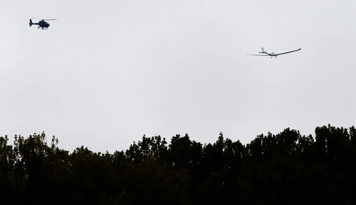 Sebuah helikopter mengikuti pesawat SolarStratos stratosfer bertenaga surya selama penerbangan uji pertama di Payerne, Swiss (5/5). (AFP Photo/Fabrice Coffrini)
