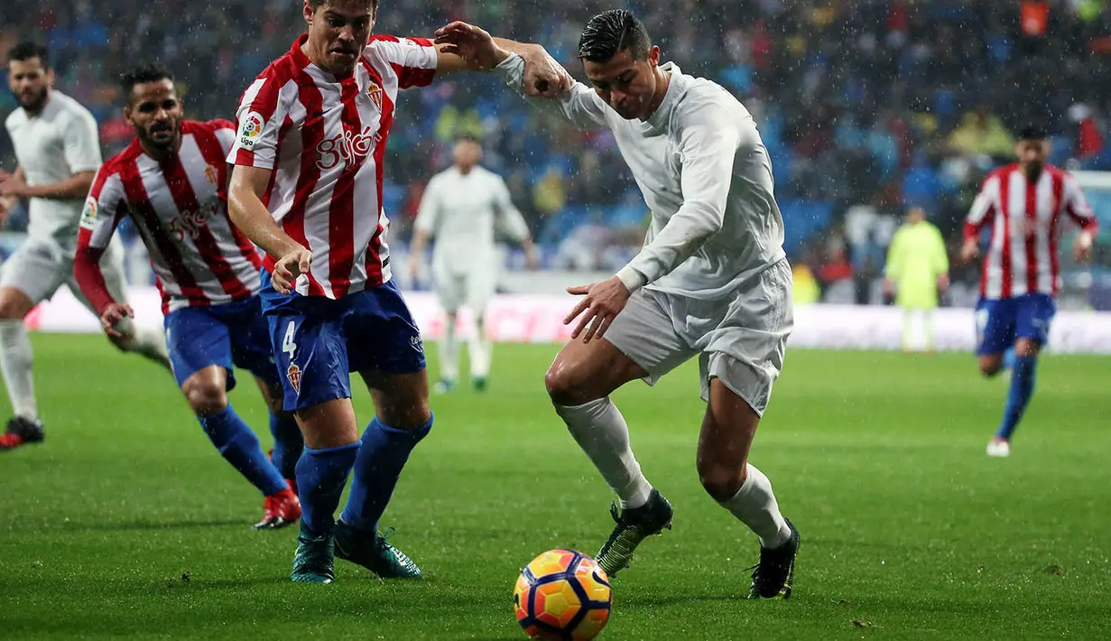 Penyerang Real Madrid, Cristiano Ronaldo, berusaha melewati hadangan pemain Sporting Gijon. Gol kedua Ronaldo tercipta pada menit ke-18 melalui umpan Nacho. (Reuters/Susana Vera)
