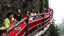 Wisatawan menyantap makanan pada acara perjamuan di sepanjang tepi tebing di Laojun Mountain provinsi Henan, China. Wisatawan menikmati berbagai suguhan makanan di jalanan selebar enam kaki yang menempel pada tebing setinggi 2.000 meter. (AFP)