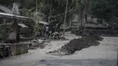 Warga membersihkan abu dan lumpur di sekitar rumah yang rusak di Dusun Kamar Kajang, Lumajang, Kamis (9/12/2021). Luapan air sungai bercampur material lahar dingin erupsi Gunung Semeru merendam puluhan rumah akibat diguyur hujan deras pada Selasa (7/12) dan Rabu (8/12) malam. (Juni Kriswanto/AFP)