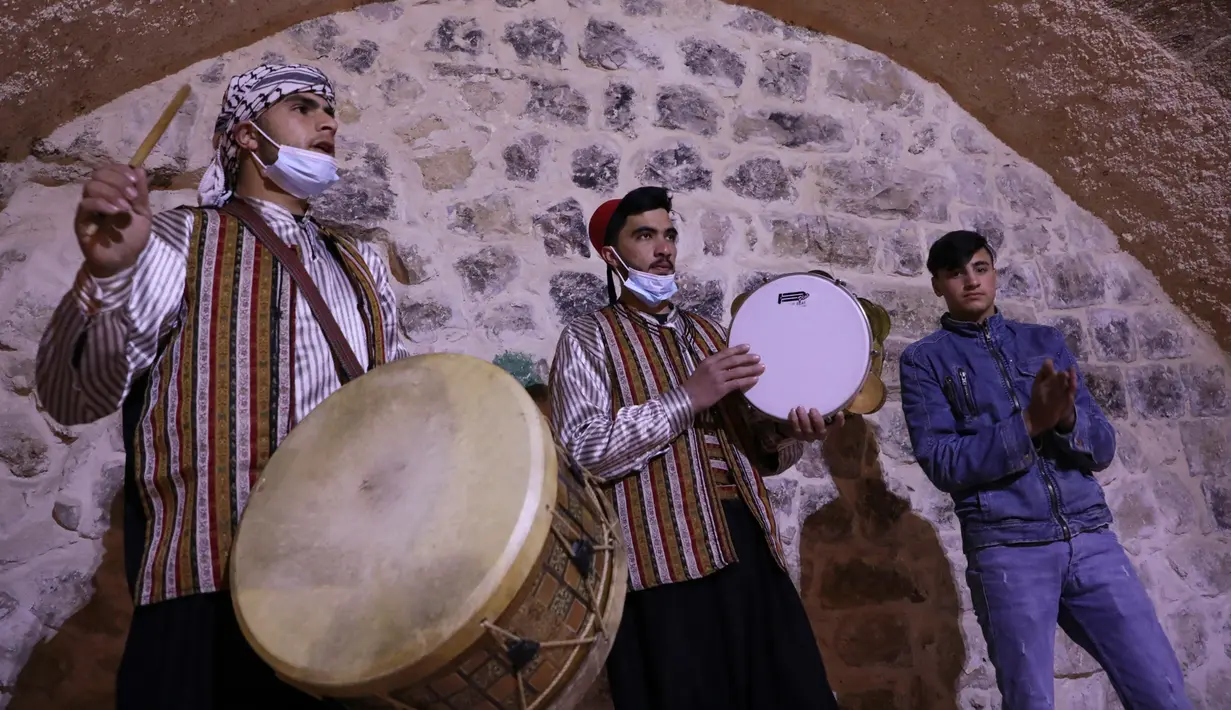 Pria Palestina yang dikenal dengan "Musaharatis" saat bertugas sebagai "penabuh drum Ramadhan" di kota tua Hebron, Tepi Barat pada 14 April 2021. Mereka menyusuri jalan-jalan kota, masuk ke gang-gang kecil untuk membangunkan umat Islam sahur selama bulan Ramadhan. (HAZEM BADER/AFP)